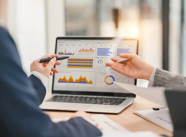 Marketing professionals analysing PPC performance metrics on a digital dashboard during a client meeting.