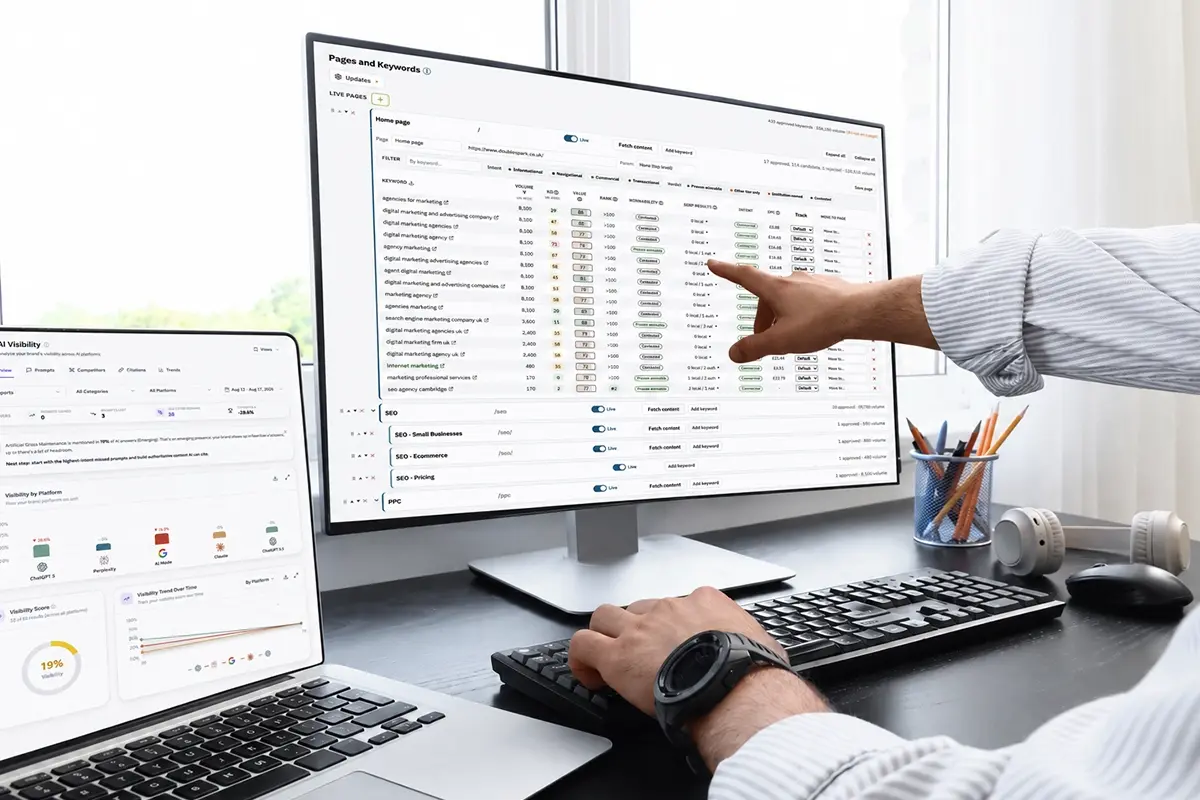 SEO specialist reviewing keyword rankings and AI visibility data across desktop and laptop screens.