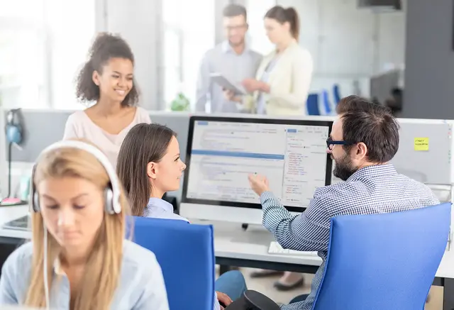 Marketing team reviewing digital ad performance and HTML code on-screen in a modern office setting, discussing display advertising strategy.