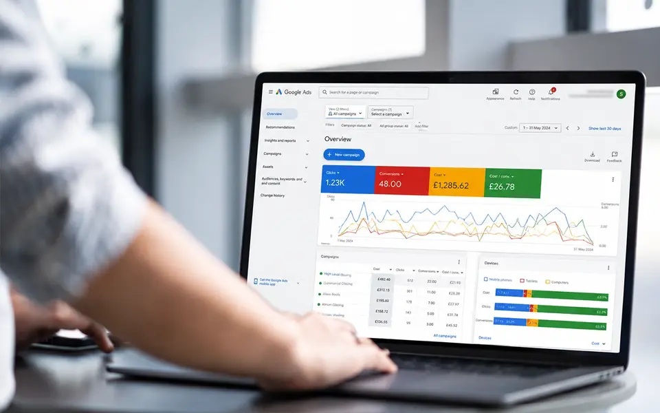 Google Ads dashboard on a laptop displaying PPC campaign clicks, conversions, costs and performance data.