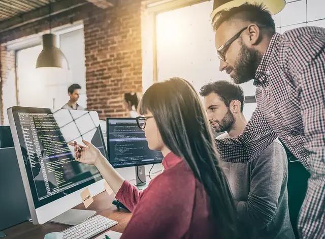 Digital marketing team reviewing campaign performance data on computer monitors in a modern office setting.