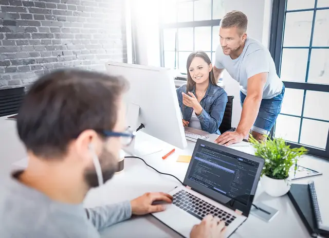 Digital marketing team collaborating on a remarketing campaign strategy, reviewing ad performance data and coding display ad scripts in a modern office setting.