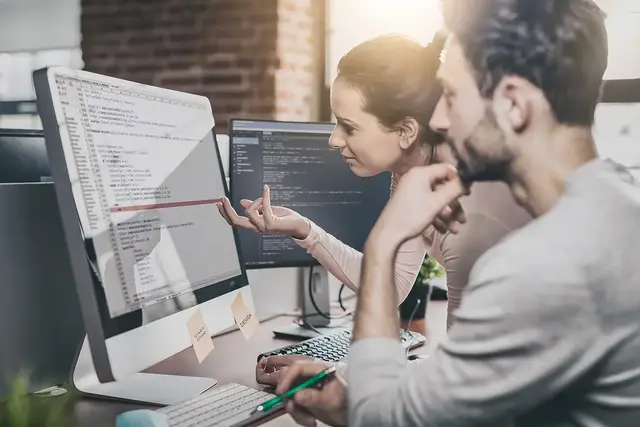 Two SEO specialists analysing website code and discussing technical issues on-screen, representing penalty recovery and SEO troubleshooting processes.