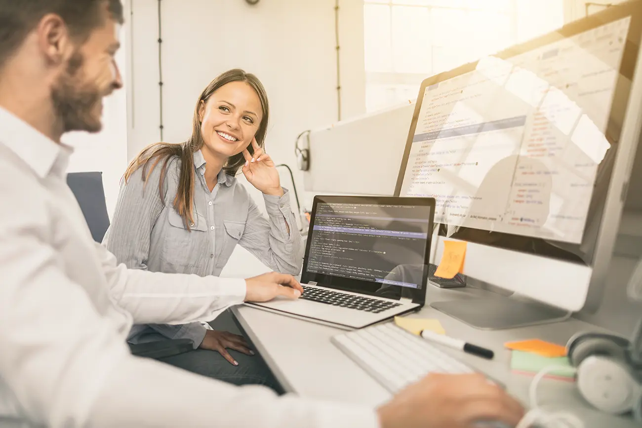 Two Doublespark team members discussing SEO strategy while reviewing code and analytics on screen in a collaborative office environment.
