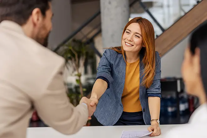 Businesswoman shaking hands with a client, representing a senior-led growth partnership